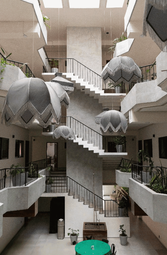 Vista del patio central con escalera, plantas y mesa en planta baja
